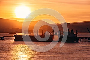 Cargo freight ship in harbour in dramatic sunset view, water transportation and vessel logistic