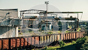 Cargo freight train wagons go on railroad in industrial zone with plants and manufacturing factories