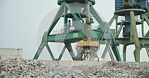 A cargo magnetic crane unloads the cast iron onto the pier. Business concept, logistics of transportation by sea