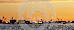 Cargo port of Rotterdam during colorful sunset, the largest port in the Netherlands. Cranes and containers. Banner format