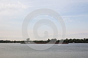 Cargo ship, a barge, cruising on the Danube river in Serbia, in belgrade, carrying construction material.