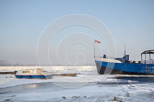 Cargo ship and a boat trapped on Frozen Danube during the 2017 winter, in Zemun, Belgrade, Serbia with ice popping out of water.