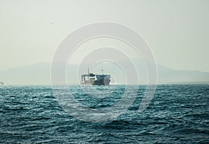 Cargo ship and boats floating in blue sea on skyline background. Feight ship in blue ocean on horizon landscape.