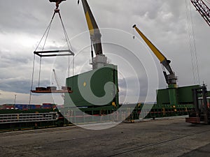 A cargo ship and cranes and machinery in the port of Bilbao, Spain, one morning at dawn