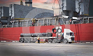 Cargo ship discharging steel wire rod at port terminal. Truck load steel cargo at seaport. General cargo logistics transportation