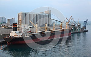 Cargo ship docked to industrial port photo
