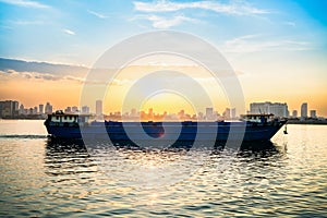 Cargo ship and dry bulk vessel at sunset. Export or import in Asia. Grain or wheat transportation.