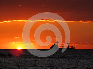 Cargo ship floatin in beautiful sunset.