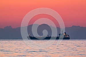 Cargo ship floating on the sea in the evening with the mountains