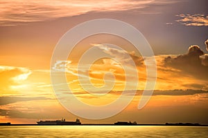 Cargo ship floats on the ocean at sunset time