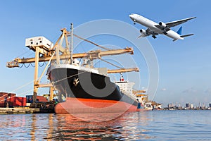 Cargo ship in the harbor and cargo plane flying above ship port