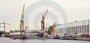 Cargo ship loading cranes in industrial zone on river, freight logistic transportation by water concept