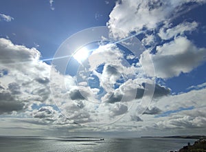 Cargo ship in the open sea. White clouds on a blue sunny sky background and sea
