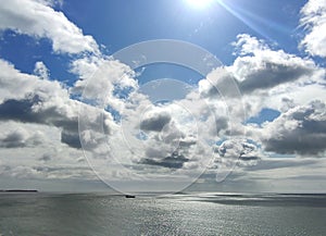 Cargo ship in the open sea. White clouds and sea background