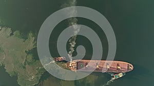 Cargo ship polluting air with smoke, aerial top down view