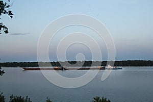 Cargo ship sailing on a big river at summer day