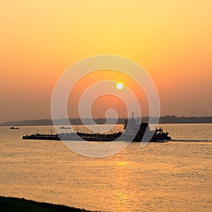 Cargo ship sailing at sunset