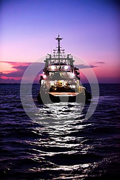 Cargo ship on the sea arriving to the harbor by night