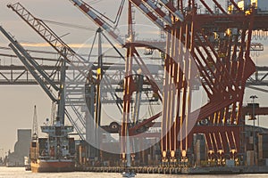 A cargo ship stands in a seaport with huge loading cranes