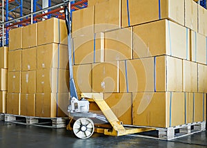 Cargo shipment boxes. Commercial warehousing. Stack of cartons product boxes and hand pallet truck at the warehouse storage.