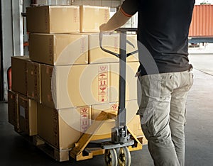 Cargo shipment boxes, Warehousing. Worker working with hand pallet truck unloading cargo boxes on pallet at the warehouse.