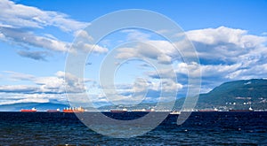 Cargo ships in bay under clouds and blue sky