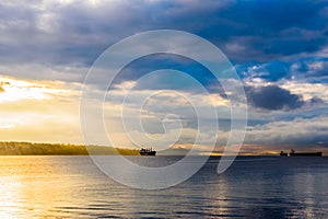 Cargo ships at cloudy sunset in bay