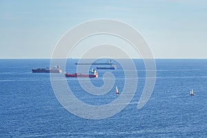 Cargo ships Freighters anchored at Mediterranean Sea and sailboats sailing