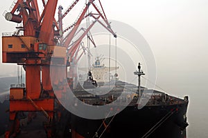 Cargo terminal for discharging coal cargos by shore cranes during foggy weather. Port Bayuquan,China.