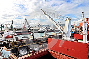Cargo terminal for unloading steel plates from bulk carrier by ships cranes.  Port of Cigading. Indonesia, December, 2020.