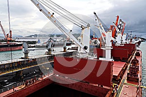 Cargo terminal for unloading steel plates from bulk carrier by ships cranes.  Port of Cigading. Indonesia, December, 2020.