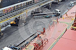 Cargo terminal for unloading steel plates from bulk carrier by ships cranes.  Port of Cigading. Indonesia, December, 2020.