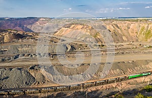 Cargo train carrying iron ore on the opencast mining quarry aerial view