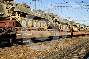 Cargo train carrying military tanks on railway flat wagons