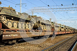 Cargo train carrying military tanks on railway flat wagons