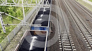 Cargo train in motion Loaded with black coal. Top view from above. Railway cargo cars. Freight train transporting fuel