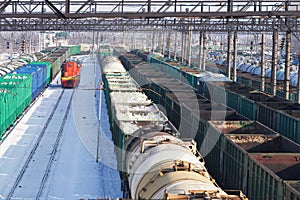 Cargo transportation by rail. Railway station with many freight trains with a variety of cargo. Winter.