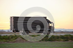 Cargo truck driving on highway hauling goods in evening. Delivery transportation and logistics concept