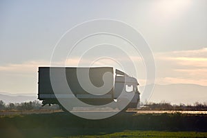 Cargo truck driving on highway hauling goods in evening. Delivery transportation and logistics concept