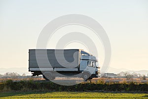 Cargo truck driving on highway hauling goods in evening. Delivery transportation and logistics concept