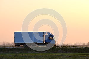 Cargo truck driving on highway hauling goods in evening. Delivery transportation and logistics concept