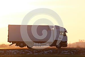 Cargo truck driving on highway hauling goods in evening. Delivery transportation and logistics concept