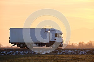 Cargo truck driving on highway hauling goods in evening. Delivery transportation and logistics concept