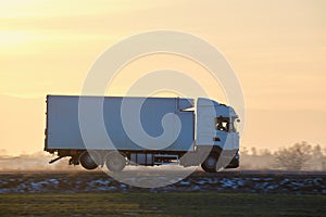 Cargo truck driving on highway hauling goods in evening. Delivery transportation and logistics concept