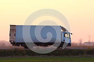 Cargo truck driving on highway hauling goods in evening. Delivery transportation and logistics concept