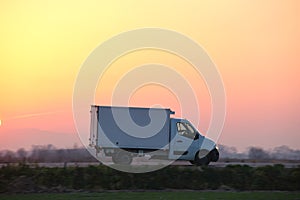 Cargo truck driving on highway hauling goods in evening. Delivery transportation and logistics concept