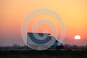 Cargo truck driving on highway hauling goods in evening. Delivery transportation and logistics concept