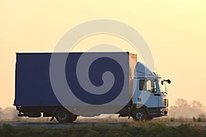 Cargo truck driving on highway hauling goods in evening. Delivery transportation and logistics concept