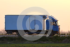 Cargo truck driving on highway hauling goods in evening. Delivery transportation and logistics concept