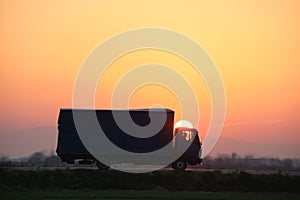 Cargo truck driving on highway hauling goods in evening. Delivery transportation and logistics concept